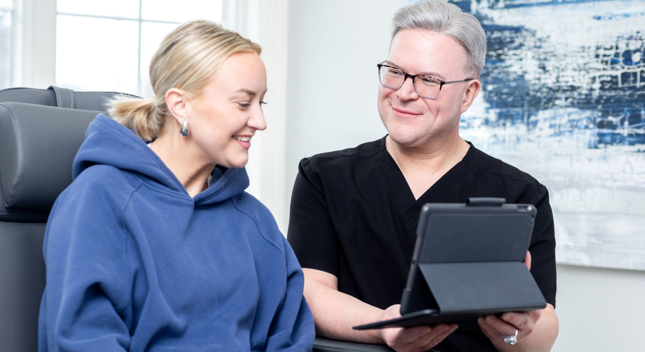 Matt Azulay-LaFever smiling while showing a patient model something on a tablet
