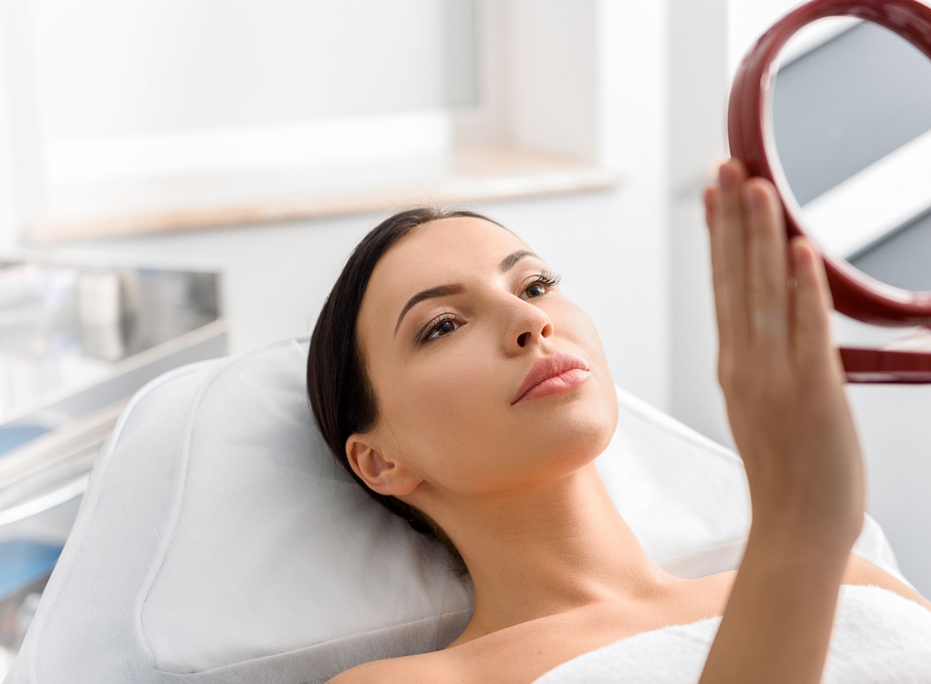med spa patient model lookin in a small handheld mirror