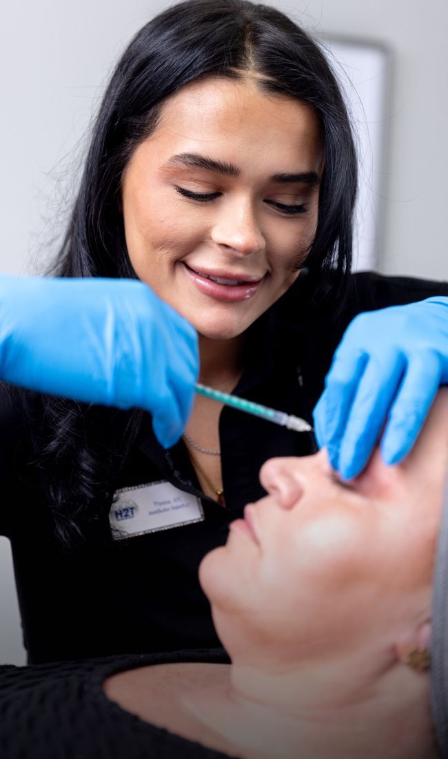 aesthetic training student model injecting botox into a patient model's brtow